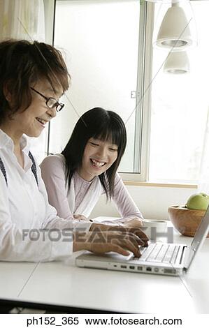 Stock Photography - Side profile of a senior woman using a laptop with her granddaughter sitting beside her. Fotosearch