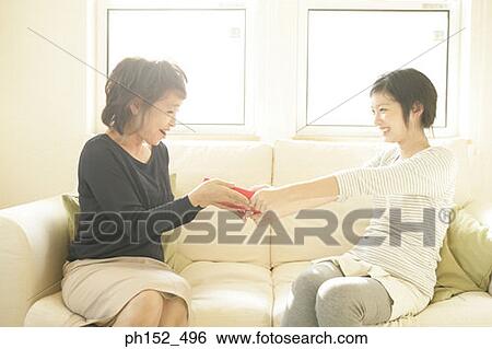 Side profile of a teenage girl giving a gift to her grandmother View Large Photo Image Stock Photograph - Side profile of a teenage girl giving a gift to her grandmother. Fotosearch