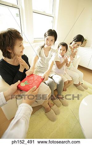 Teenage girl sitting with her family and taking a gift View Large Photo Image Stock Image - Teenage girl sitting with her family and taking a gift. Fotosearch