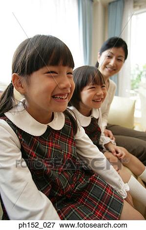 Two girls and their mother sitting on a couch and smiling View Large Photo Image Stock Photo - Two girls and their mother sitting on a couch and smiling. Fotosearch