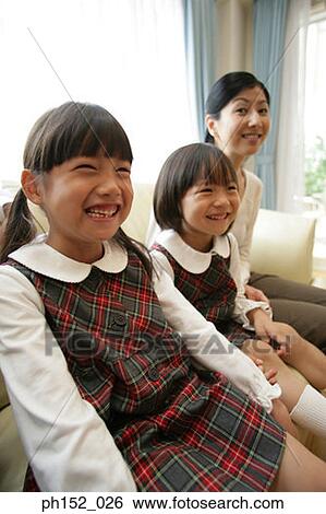 Two girls and their mother sitting on a couch and smiling View Large Photo Image Stock Photograph - Two girls and their mother sitting on a couch and smiling. Fotosearch