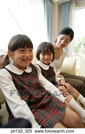Two girls and their mother sitting on a couch and smiling View Large Photo Image Stock Photography - Two girls and their mother sitting on a couch and smiling. Fotosearch
