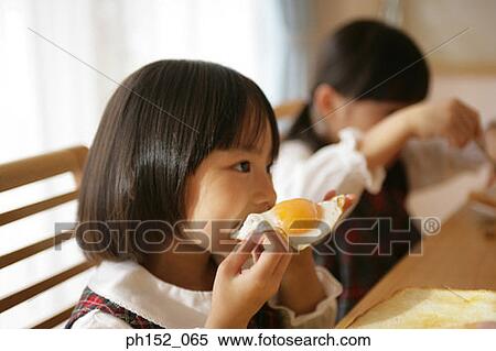 Stock Photography - Two girls having breakfast at the dining table. Fotosearch