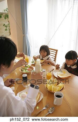 Two girls having breakfast with their parents View Large Photo Image Stock Image - Two girls having breakfast with their parents. Fotosearch