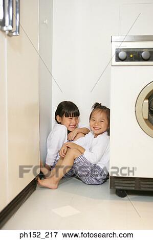 Two girls sitting in a corner near a washing machine View Large Photo Image Stock Photo - Two girls sitting in a corner near a washing machine. Fotosearch