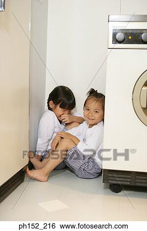 Two girls sitting in a corner near a washing machine View Large Photo Image Stock Photograph - Two girls sitting in a corner near a washing machine. Fotosearch