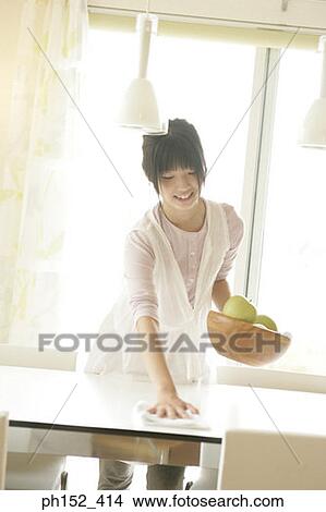 Young woman cleaning the table and holding a bowl of apples View Large Photo Image Picture - Young woman cleaning the table and holding a bowl of apples. Fotosearch