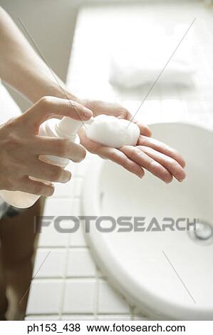 Stock Photo - Close-up of a woman's hand squeezing a bottle of soap suds. Fotosearch