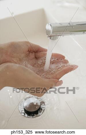 Stock Photography - Close-up of a woman's hands cupped under a faucet. Fotosearch