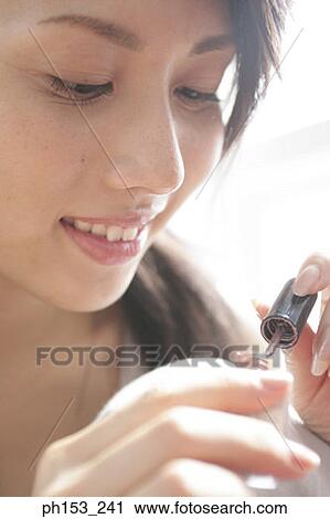 Close-up of a young woman applying nail polish on her fingernails View Large Photo Image Stock Image - Close-up of a young woman applying nail polish on her fingernails. Fotosearch