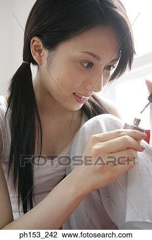 Close-up of a young woman applying nail polish on her fingernails View Large Photo Image Stock Image - Close-up of a young woman applying nail polish on her fingernails. Fotosearch