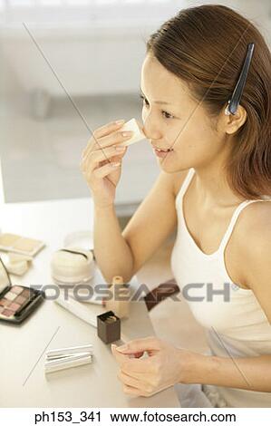 Stock Image - Close-up of a young woman applying make-up. Fotosearch