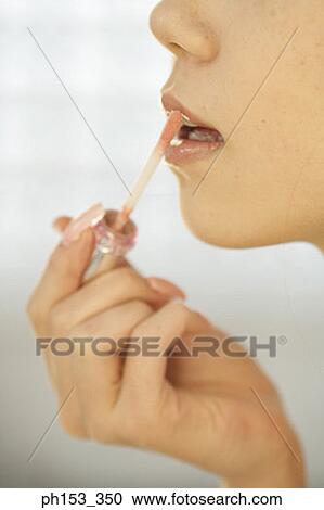 Close-up of a young woman applying lipstick View Large Photo Image Stock Image - Close-up of a young woman applying lipstick. Fotosearch