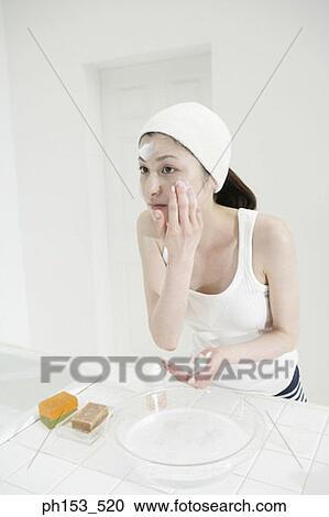 Close-up of a young woman applying moisturizer on her face View Large Photo Image Stock Image - Close-up of a young woman applying moisturizer on her face. Fotosearch