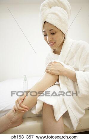 Stock Photo - Close-up of a young woman applying moisturizer on her leg. Fotosearch