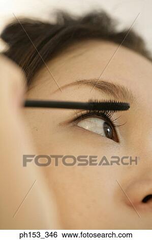 Close-up of a young woman applying mascara View Large Photo Image Stock Photograph - Close-up of a young woman applying mascara. Fotosearch