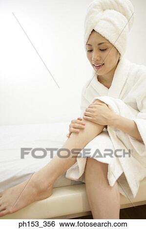 Stock Photograph - Close-up of a young woman applying moisturizer on her leg. Fotosearch