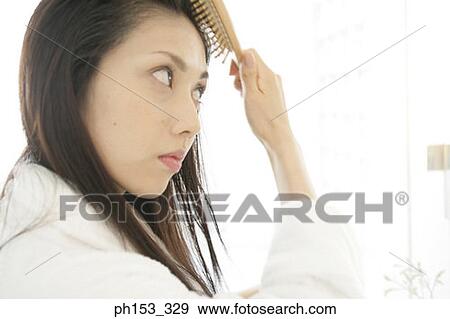 Close-up of a young woman brushing her hair View Large Photo Image Stock Photo - Close-up of a young woman brushing her hair. Fotosearch