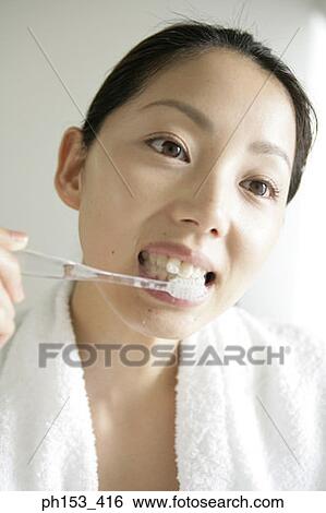 Stock Photograph - Close-up of a young woman brushing her teeth. Fotosearch
