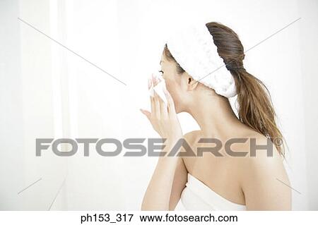 Close-up of a young woman cleaning her face with a tissue paper View Large Photo Image Stock Photo - Close-up of a young woman cleaning her face with a tissue paper. Fotosearch