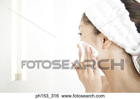 Close-up of a young woman cleaning her face with a tissue paper View Large Photo Image Stock Photograph - Close-up of a young woman cleaning her face with a tissue paper. Fotosearch