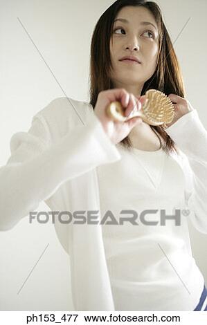 Close-up of a young woman combing her hair View Large Photo Image Stock Photo - Close-up of a young woman combing her hair. Fotosearch