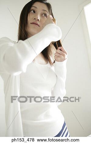 Close-up of a young woman combing her hair View Large Photo Image Stock Photo - Close-up of a young woman combing her hair. Fotosearch