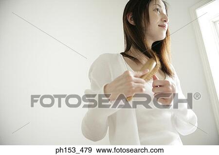 Close-up of a young woman combing her hair View Large Photo Image Stock Photo - Close-up of a young woman combing her hair. Fotosearch