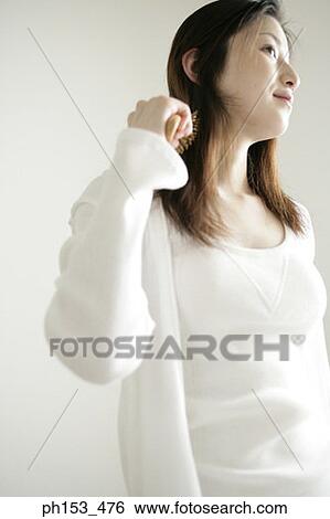 Close-up of a young woman combing her hair View Large Photo Image Stock Photograph - Close-up of a young woman combing her hair. Fotosearch