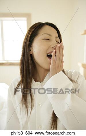 Close-up of a young woman covering her mouth with her hand and yawning View Large Photo Image Picture - Close-up of a young woman covering her mouth with her hand and yawning. Fotosearch