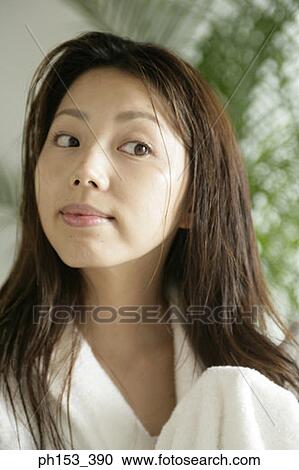 Stock Image - Close-up of a young woman drying her hair with a towel. Fotosearch