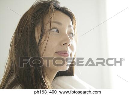 Stock Image - Close-up of a young woman drying her hair with a towel. Fotosearch