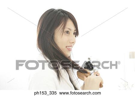Close-up of a young woman drying her hair with a hair dryer and smiling View Large Photo Image Stock Photography - Close-up of a young woman drying her hair with a hair dryer and smiling. Fotosearch