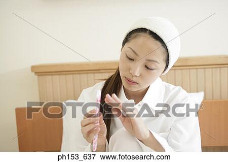 Close-up of a young woman filing her nails View Large Photo Image Stock Photo - Close-up of a young woman filing her nails. Fotosearch