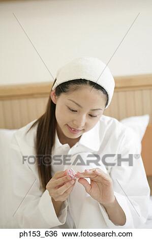 Stock Photograph - Close-up of a young woman filing her nails. Fotosearch