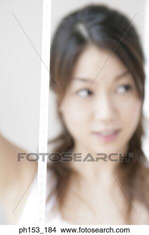 Close-up of a young woman holding a tape measure and smiling View Large Photo Image Picture - Close-up of a young woman holding a tape measure and smiling. Fotosearch