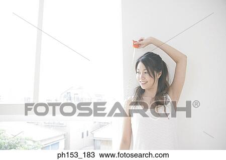 Stock Image - Close-up of a young woman holding a tape measure and smiling. Fotosearch