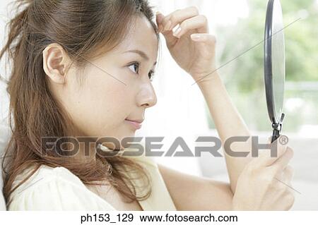 Close-up of a young woman holding a vanity mirror View Large Photo Image Stock Photo - Close-up of a young woman holding a vanity mirror. Fotosearch