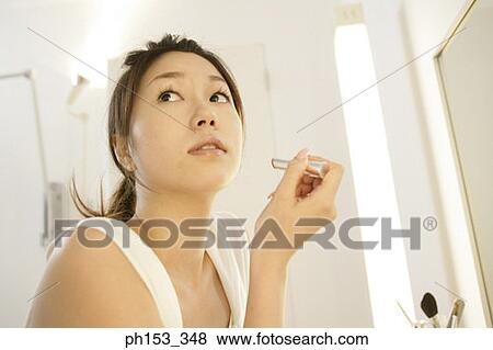 Close-up of a young woman holding a lipstick and looking sideways View Large Photo Image Stock Photo - Close-up of a young woman holding a lipstick and looking sideways. Fotosearch