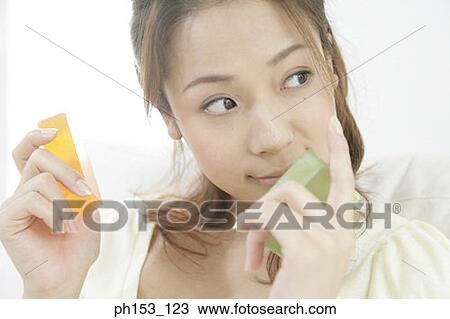 Stock Image - Close-up of a young woman holding two bars of soap. Fotosearch