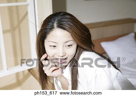 Close-up of a young woman leaning out of a window and smiling View Large Photo Image Stock Photo - Close-up of a young woman leaning out of a window and smiling. Fotosearch