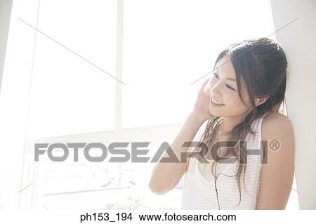 Close-up of a young woman listening to music and looking cheerful View Large Photo Image Picture - Close-up of a young woman listening to music and looking cheerful. Fotosearch