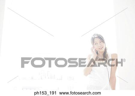 Close-up of a young woman listening to music and smiling View Large Photo Image Stock Image - Close-up of a young woman listening to music and smiling. Fotosearch