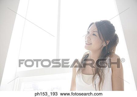 Close-up of a young woman listening to music and smiling View Large Photo Image Stock Image - Close-up of a young woman listening to music and smiling. Fotosearch
