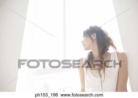 Close-up of a young woman listening to music with her eyes closed View Large Photo Image Stock Photograph - Close-up of a young woman listening to music with her eyes closed. Fotosearch