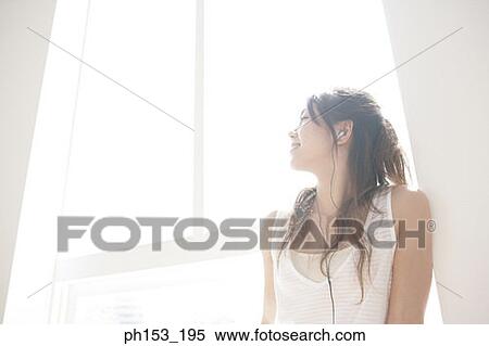 Close-up of a young woman listening to music and looking cheerful View Large Photo Image Stock Photography - Close-up of a young woman listening to music and looking cheerful. Fotosearch