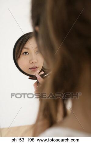 Close-up of a young woman looking in a hand mirror View Large Photo Image Stock Photo - Close-up of a young woman looking in a hand mirror. Fotosearch