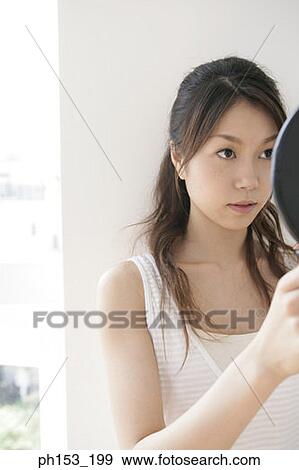 Close-up of a young woman looking in a hand mirror View Large Photo Image Stock Photo - Close-up of a young woman looking in a hand mirror. Fotosearch