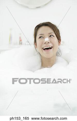 Stock Photography - Close-up of a young woman looking cheerful in a bathtub. Fotosearch