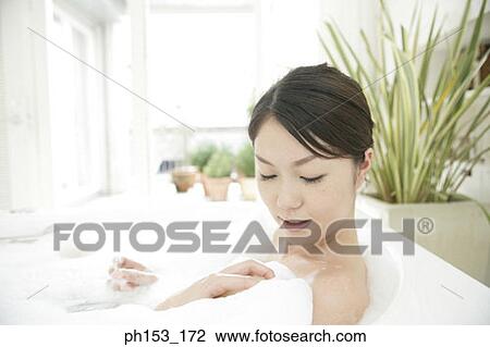 Close-up of a young woman relaxing in a bubble bath and smiling View Large Photo Image Stock Image - Close-up of a young woman relaxing in a bubble bath and smiling. Fotosearch